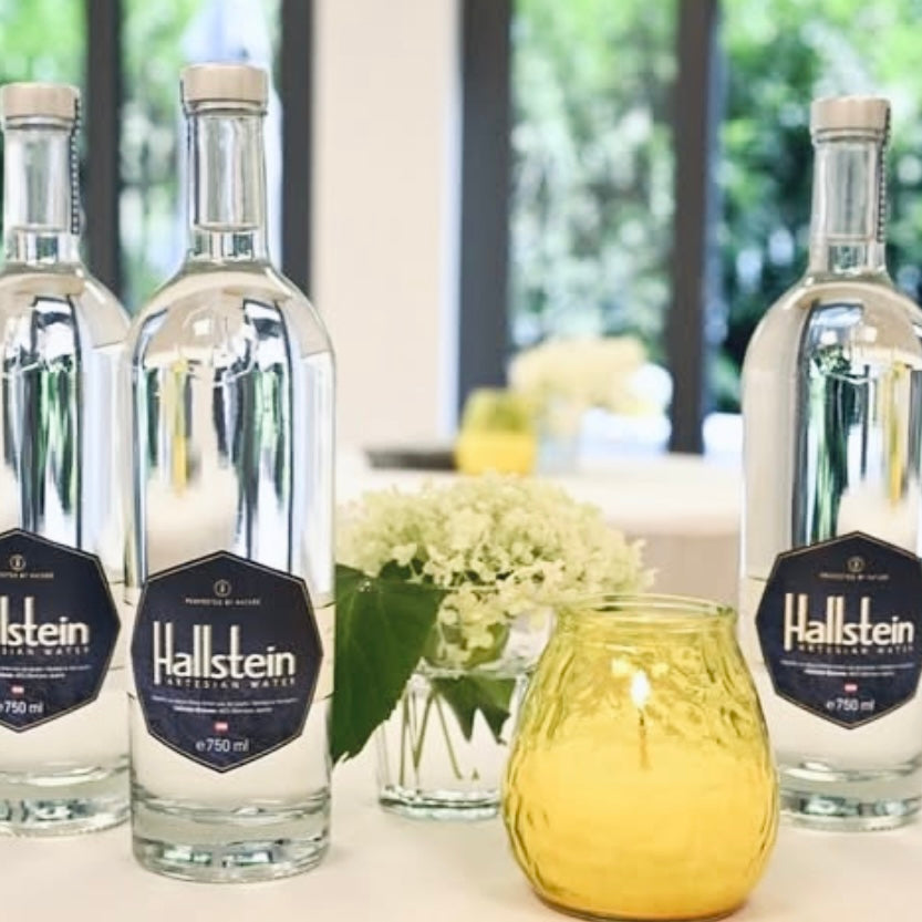 Hallstein bottles on a table with a yellow candle and floral arrangement for a special occasion